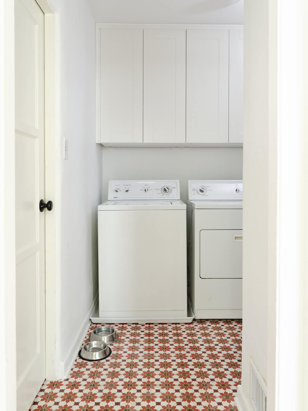laundry room with white cabinets and geometric patterned tiles after renovation