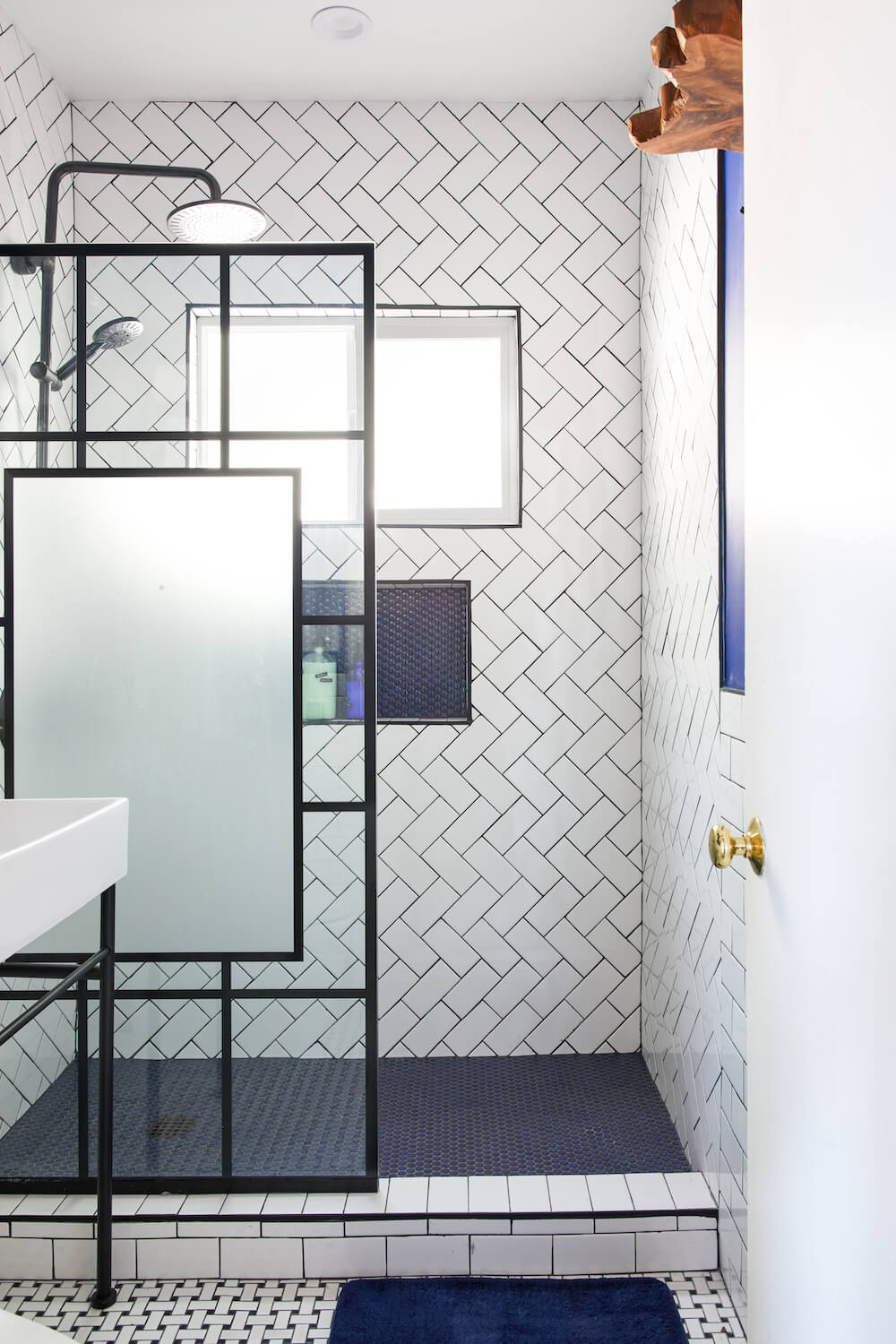 blue bathroom remodel in Los Angeles with herringbone shower tile and frosted shower panel