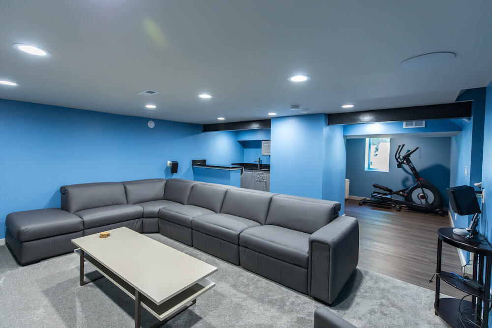 Low white ceiling with blue walls in the entertainment room and fitness equipment after renovation
