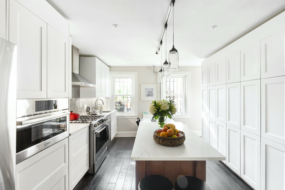 Kitchen with white floor-to-ceiling cabinets, dark hardwood floors, and white countertop kitchen island