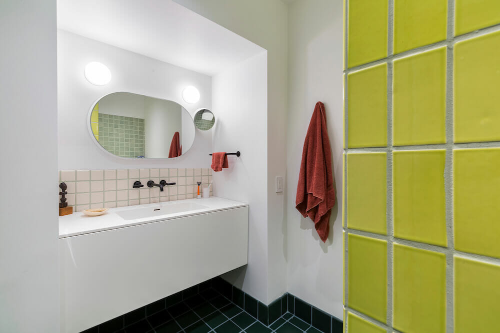 White bathroom with yellow wall tile and oval mirror bronx rowhouse remodel