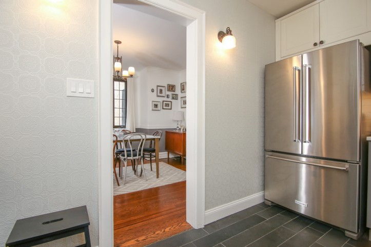 gray wallpaper in a kitchen with dark floor tiles and double door refrigerator after renovation